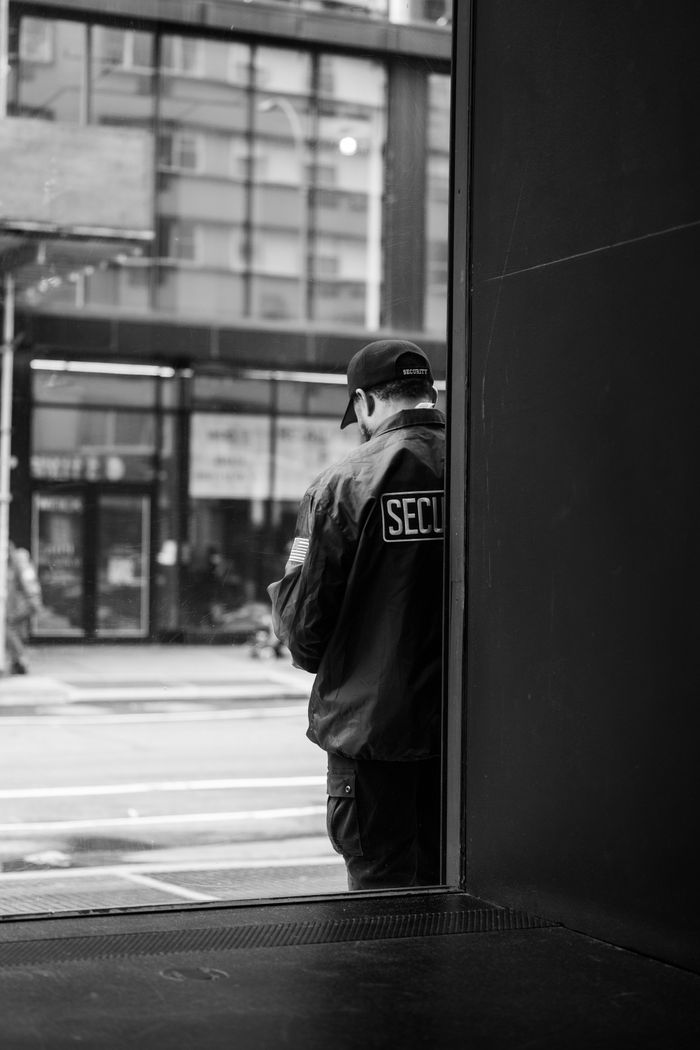 Crafting Captivating Headlines: Your awesome post title goes here A solitary security guard stands in an urban street, captured in monochrome, evoking a sense of loneliness.